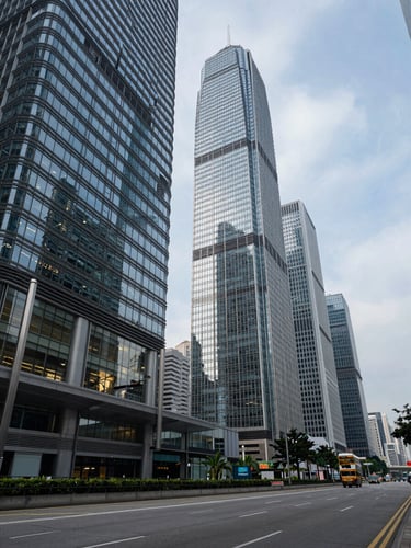 Wide panoramic Hong Kong financial district at cool midday light, glass towers of Central receding into the right frame, a single floor of a trading floor visible through a lower window, empty foreground street reflecting grey sky, deep architectural perspective