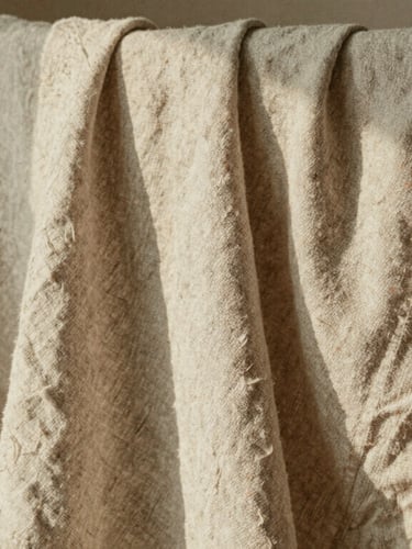 Tactile macro texture of slubby linen fabric draped over a wooden chair, soft afternoon shadows, warm earth tones, 35mm film grain.
