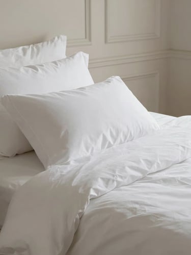 Portrait composition of a beautifully dressed bed with crisp white linens, high-thread-count cotton, soft natural light, classic Parisian moldings in the soft background.