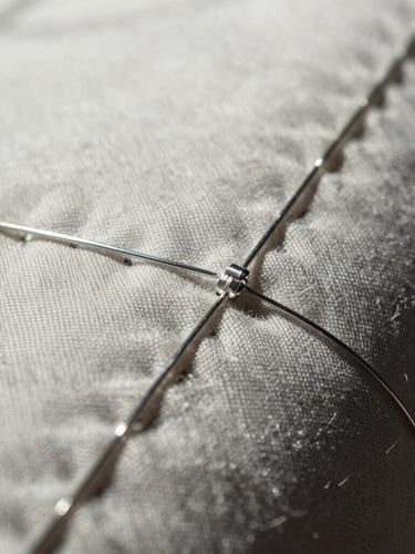 Extreme close-up of raw upcycled textile seams and metallic silver threads, high contrast, direct bright sunlight.