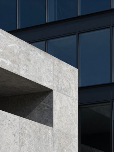 Close-up architectural detail of a minimalist concrete and glass structure, sharp shadows, cool gray slate tones, clean geometric lines.