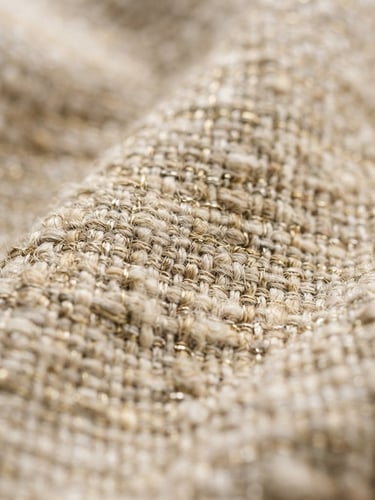 Close-up of premium cotton textile texture, soft morning window light, rich neutral tones with gold highlights, shallow depth of field, 35mm