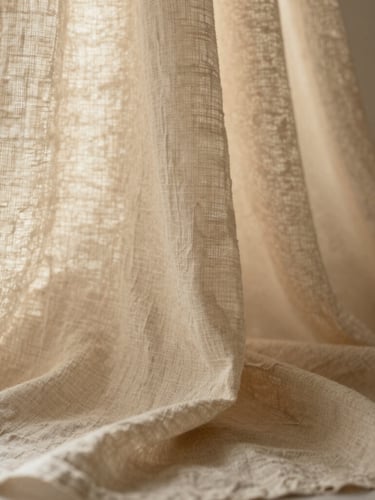 Close-up of soft beige linen fabric texture draped elegantly under warm diffused sunlight, quiet organic feel