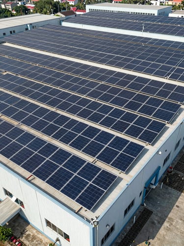 Wide-angle drone photograph of a massive, perfectly aligned coplanar rooftop solar array on an industrial building in Chakan, bright midday sun, high-contrast shadows.