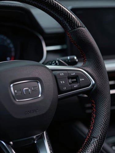 Macro close-up of a luxury modern vehicle steering wheel, brushed silver accents, carbon fiber textures, dramatic low-key studio lighting with sharp highlights