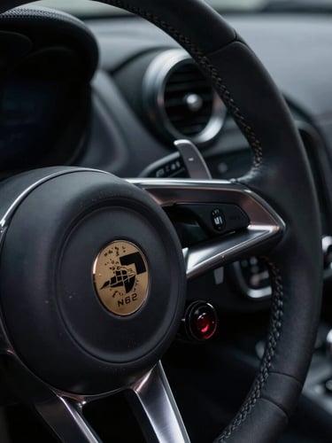 Tight macro portrait shot of a luxury sports car steering wheel and brushed silver dashboard details, low-key dramatic lighting, sharp focus