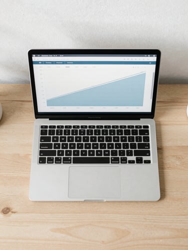 Flat-lay overhead shot of a minimalist wooden workspace, a laptop showing a clean line chart with slate blue accents, soft overcast daylight, 35mm lens