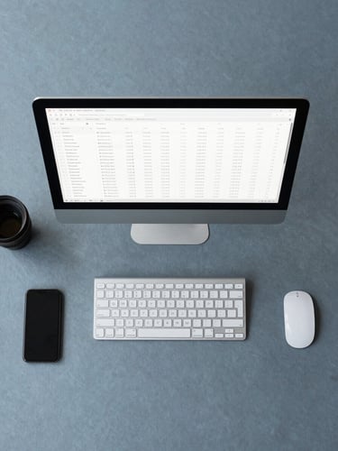 Flat-lay overhead shot of a minimalist workspace, cool slate blue and charcoal tones, soft overcast daylight, sharp focus on a clean screen showing structured data tables