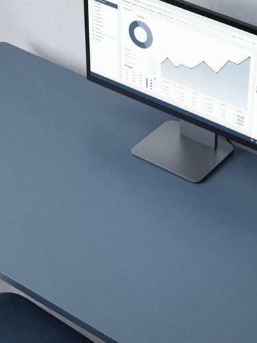 Overhead flat-lay of a structured minimalist desk with a screen displaying clean, high-contrast data charts, soft overcast daylight, slate blue tones.