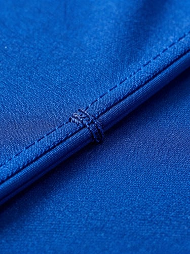 Macro close-up of high-contrast electric blue sportswear fabric, showcasing detailed flatlock stitching precision under dramatic studio lighting.