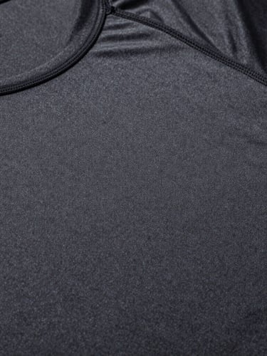 Macro overhead studio shot, high-contrast crisp lighting, technical flat-lay of a charcoal athletic compression shirt showing precise flatlock stitching details, cool undertones, negative space.