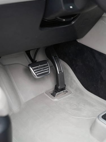 Close-up of clean car footwell and pedals, professional automotive photography, bright overcast daylight, sharp focus on metal textures, 50mm lens