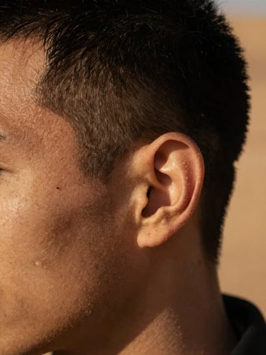 Macro close-up of a sharp, clean fade on a model's temple, dramatic side-lighting casting deep shadows, warm desert sand tones, 35mm.