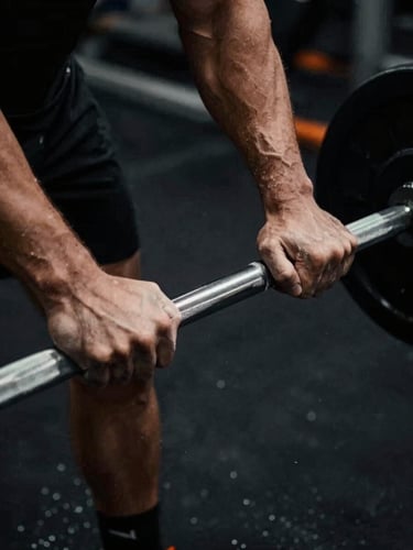 Close-up of hands gripping a knurled steel barbell, chalk dust in the air, high-contrast dramatic lighting, deep shadows, desaturated tones, 35mm film.