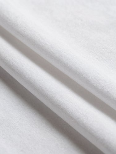 Macro close-up of perfectly aligned, crisp white cotton sheets under bright, natural daylight, showing fine fabric texture, minimal composition.