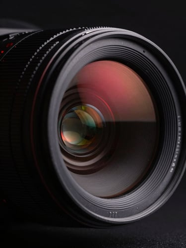 Extreme close-up of a high-contrast digital camera lens reflecting red neon studio light, sharp angles, deep black shadows, minimalist composition