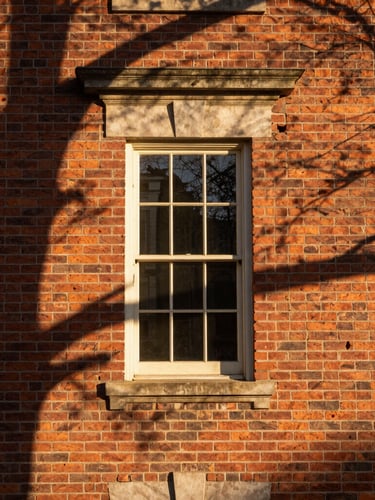 Architectural detail of a historic brick facade in Leesburg, warm morning light casting long shadows, rich textures, editorial framing