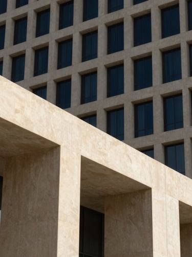 Architectural close-up of a modern Dubai government ministry building, sharp geometric concrete lines under intense desert sun, deep shadows, navy tones