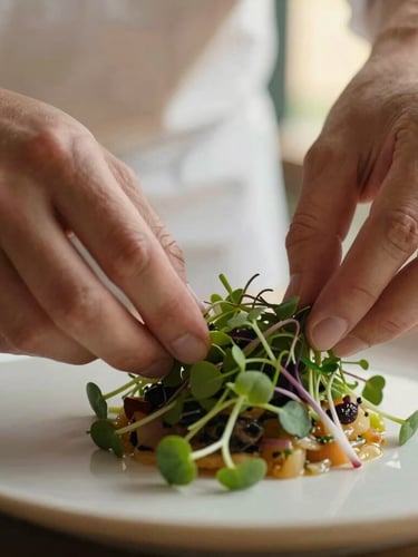 Macro close-up of a chef's hands gently arranging fresh microgreens on an artfully plated seasonal dish, soft golden hour light, shallow depth of field, focus on food texture.