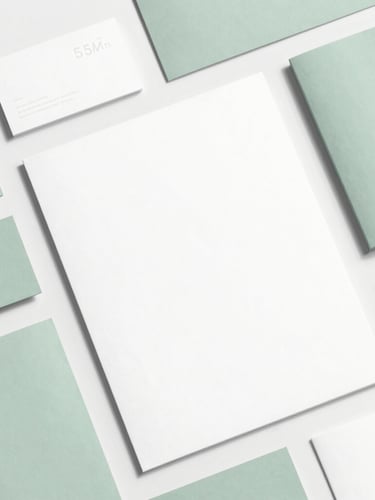 High-quality flat-lay of elegant printed brand collateral (business cards, letterhead, brochures) with subtle sage green accents, minimalist composition, bright natural daylight, 35mm