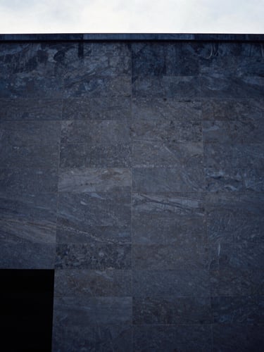 Editorial film photography, cool overcast daylight, deep navy tones, a minimalist architectural crop of a modern limestone facade in Paris, 35mm composition.