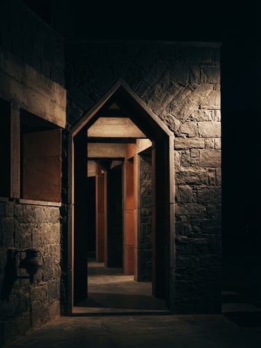 Low-key dramatic side-lighting on a modern stone archway of an elite Indian public policy institute, deep midnight-slate shadows, subtle terracotta reflections, 50mm