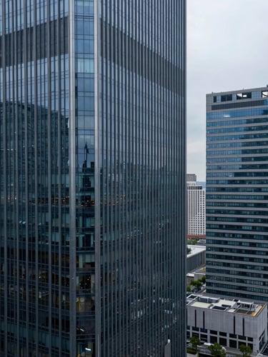 High-angle architectural shot of corporate skyscrapers with clean glass facades reflecting cool overcast daylight, projecting permanence and financial security.