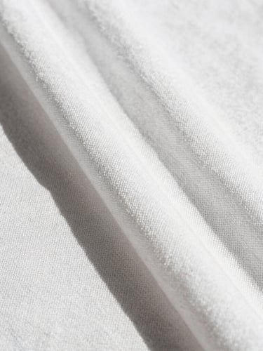 Extreme close-up of a premium white linen fabric weave, showing the rich organic texture and cross-hatched threads under bright direct sunlight with sharp shadows.