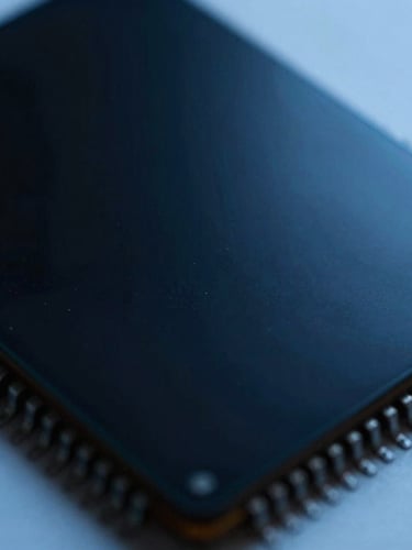 Extreme macro close-up of a physical silicon microchip wafer, cool-toned high-contrast studio lighting, deep blacks and electric blue highlights, macro lens
