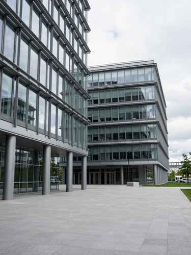 A wide-angle environmental shot of clean, modern architectural lines inside a Swiss corporate headquarters, structured steel and glass facade, overcast daylight, clinical framing.