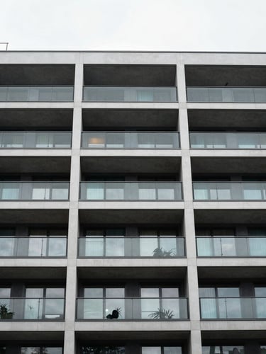 Low-angle architectural portrait of a modern multi-story residential building facade in London, clean glass balconies, crisp overcast daylight
