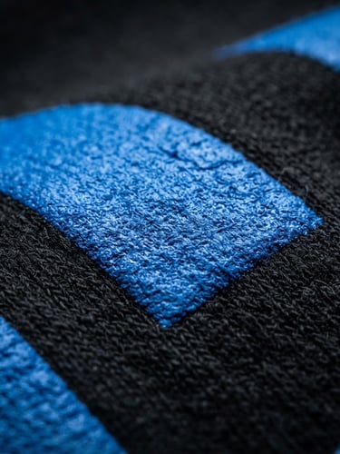 Close-up of high-quality electric blue ink texture printed on a heavy black cotton hoodie, dramatic studio rim lighting, macro 35mm photography