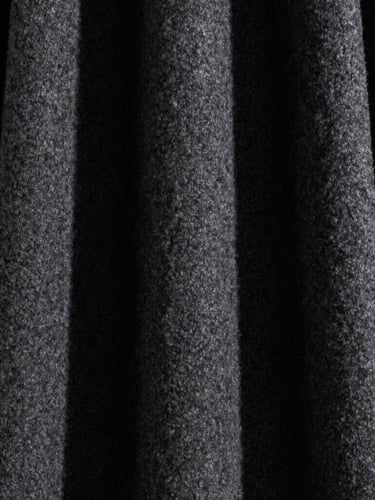 Extreme close-up of heavy structured charcoal wool drape, sharp directional studio light, deep shadows, high-contrast minimalist editorial fashion photography