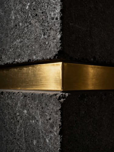 Extreme close-up of premium textured raw concrete meeting a brushed gold steel joint, dramatic side lighting, architectural detail, high contrast, 35mm