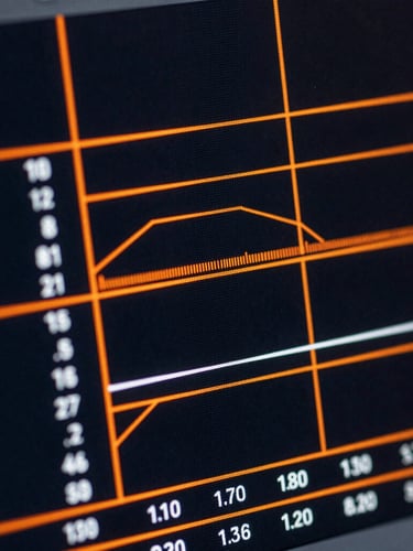 Extreme close-up of a high-contrast digital interface displaying real-time data visualizations, sharp orange accent lines on a dark screen
