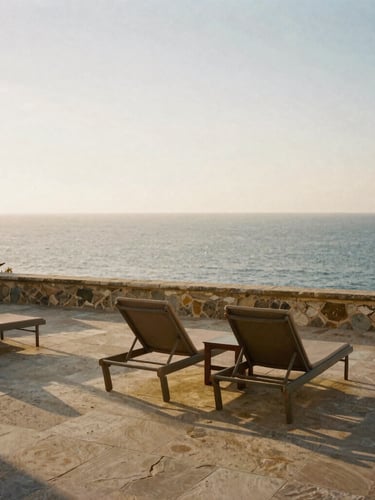 Serene sun-drenched stone terrace overlooking the Mediterranean sea at golden hour, empty elegant lounge chairs, warm side-light, editorial luxury travel photography, 35mm film aesthetic