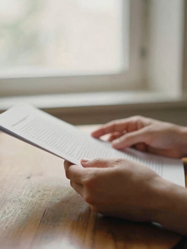 A close-up of hands gently holding a document over a wooden table, soft morning window light, warm editorial photography, 35mm