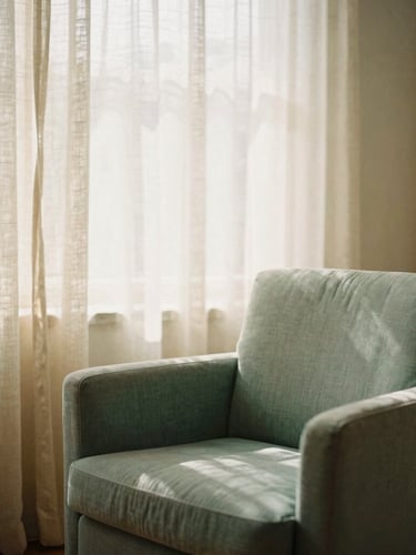 Warm editorial photography of a peaceful consulting room, soft morning window light filtering through linen curtains, comfortable sage green armchair, warm sand tones, shallow depth of field, 35mm film
