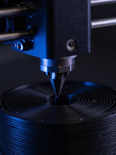Extreme macro close-up of a 3D printer nozzle depositing black PETG filament under low-key single-source lighting with a subtle blue ambient glow