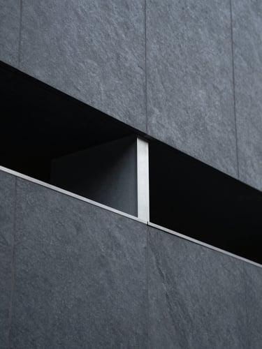 Sleek editorial photograph of modern structural geometry, dark slate and steel tones, cool diffused daylight, shallow depth of field, 35mm