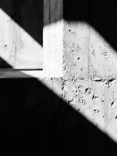 Extreme close-up of sharp architectural concrete shadows under harsh directional sunlight, high contrast black and white, minimalist composition, 35mm film grain