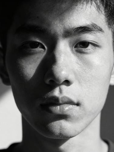 Portrait-aspect black and white close-up portrait, hard directional sunlight creating sharp geometric shadows across the face, intense expression, minimalist composition, 35mm film grain.