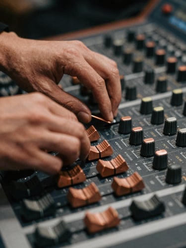 Close-up of hands adjusting copper dials on an analog mixing console, warm low-key studio lighting, soft focus, 35mm film
