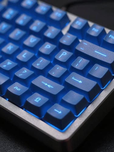 Extreme close-up of a custom mechanical keyboard with glowing electric blue keycaps, dark brushed aluminum frame, shallow depth of field, dramatic studio lighting