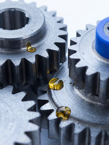 Macro close-up of clean steel mechanical gears and golden lubricant oil droplets, cool blue studio lighting, sharp focus, 50mm