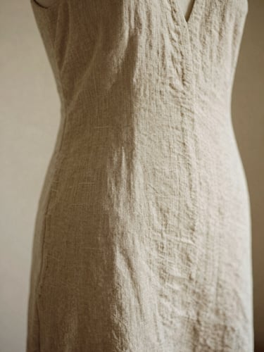 A close-up of premium neutral linen draped elegantly on a mannequin, soft natural daylight, warm sandy tones, shallow depth of field, 35mm film