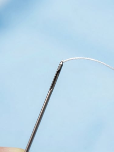 Macro photography of sterile surgical suture thread threaded through a precision curved needle, cool clinical lighting, sterile blue background.