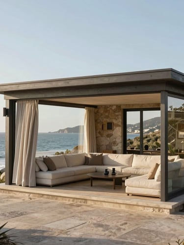 Wide-angle view of a coastal living pavilion in Clifton, open to the sea breeze, styled with neutral linens and organic stone elements.