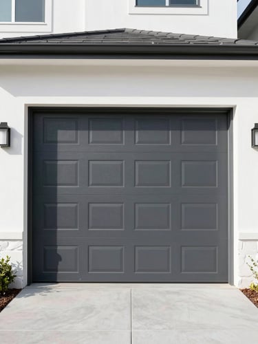 Straight-on architectural shot of a modern dark gray residential garage door on a clean coastal home, bright daylight, 35mm