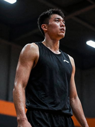 Dramatic low-angle 35mm shot of a basketball player sweating during intense court training, high-contrast spotlight, deep shadows.
